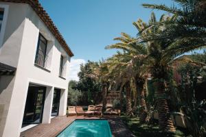 a house with a swimming pool and palm trees at La Vague - Saint Tropez in Saint-Tropez