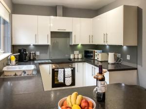 a kitchen with white cabinets and a bowl of fruit on a counter at Uppermill Farm in Tarves