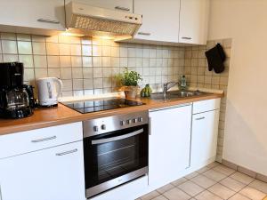a kitchen with white cabinets and a stove and a sink at Jutta vom Kutter in Wulfen auf Fehmarn