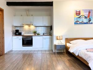 a bedroom with a bed and a kitchen with white cabinets at Jutta vom Kutter in Wulfen auf Fehmarn