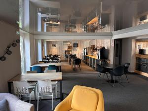 a living room with chairs and tables and a kitchen at Agape Hotel Niort- Bessines in Bessines