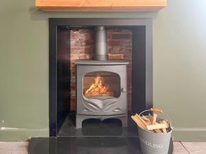 a wood stove in a room with a bucket at Forge Cottage in Canterbury