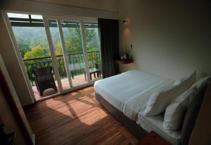 a bedroom with a bed and a balcony with a view at Ymoon Mountain Resort Wayanad in Koroth +42 photos