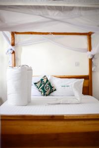 a bed with white sheets and pillows on it at Sisama Lodge in Msaranga +18 photos