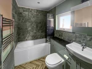 a bathroom with a tub and a toilet and a sink at Forge Cottage in Canterbury