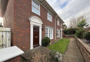 a brick house with a door and a yard at Upperton Townhouse in Eastbourne