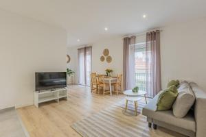 a living room with a couch and a tv and a table at Résidence Sébastopol - Appartements Hyper Centre - WiFi & Smart TV in Béziers