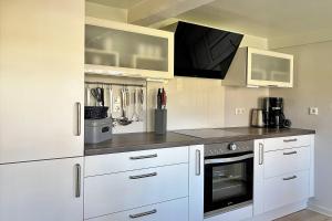a kitchen with white cabinets and a stove top oven at Haus 25 in Oldsum in Oldsum
