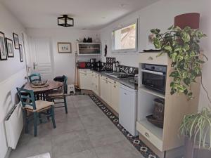 a kitchen with white cabinets and a table with a plant at Chez CoCo in Manteyer