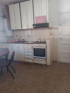 a kitchen with white cabinets and a stove top oven at La casita lila in Mar de Ajó