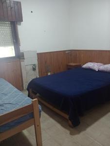 a bedroom with two beds with blue sheets and a window at La casita lila in Mar de Ajó