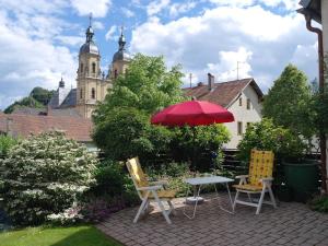 a patio with a table and chairs and a red umbrella at Ferienwohnung Haus Wagnershoehe in Gößweinstein