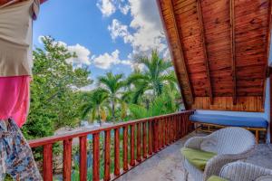 a balcony with a wooden railing and chairs and palm trees at Río Mar Cumayasa in La Romana