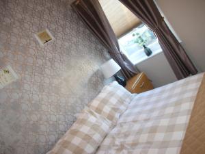 a bedroom with a bed with a checkered bedspread and a window at Sandy Creek Cottage - E5349A in Anderby +5 photos