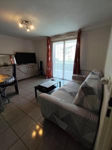 a living room with a couch and a television at nice apartment strategic location in Muret