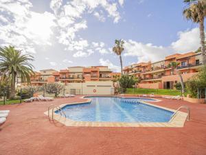 a swimming pool with palm trees and buildings at CHL La Mareta, cozy apartment with pool in Breña Baja