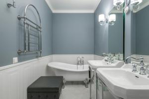 a white bathroom with two sinks and a bath tub at Hotel Square Plaza At Airport in New Delhi