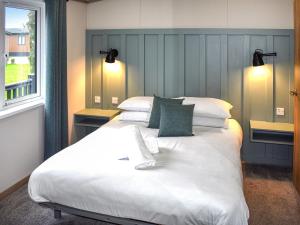 a bedroom with a large bed with white sheets and green pillows at Lodge 8 - Uk51076 in Lyme Regis +4 photos