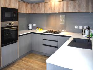 a kitchen with gray cabinets and a stove top oven at Lodge 8 - Uk51076 in Lyme Regis