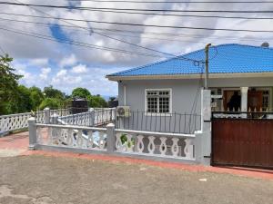 a white house with a blue roof and a fence at Sea View Guest House Apt in Kingstown