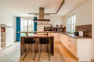 a kitchen with a wooden island with stools at Kramerhof Rügenblick Nr 30 in Parow +13 photos