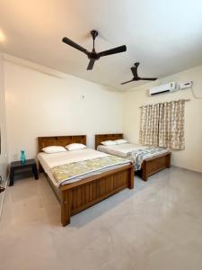 two beds in a room with a ceiling fan at Suraksha Homestay in Malpe