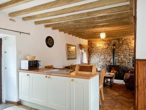 a kitchen with white cabinets and a stone wall at Honeysuckle Cottage - 27880 in Elton