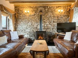 a living room with leather couches and a fireplace at Honeysuckle Cottage - 27880 in Elton