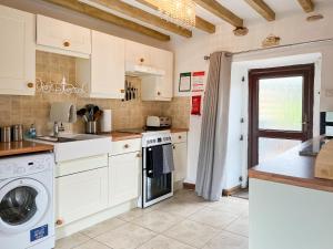 a kitchen with white cabinets and a washer and dryer at Honeysuckle Cottage - 27880 in Elton