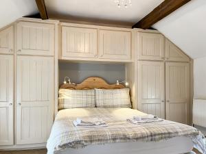 a bedroom with a bed with white cabinets at Honeysuckle Cottage - 27880 in Elton