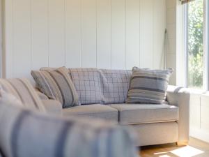 a couch in a living room with pillows on it at Nanny Goat Lodge in Crossway Green