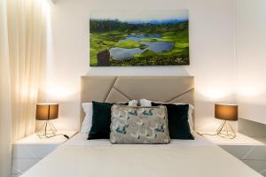 a bedroom with a white bed with two lamps at GuestReady - Passal Guesthouse in Ponta Delgada