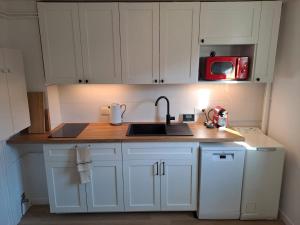 a kitchen with white cabinets and a sink and a microwave at Appartement proche Château de Compiègne in Compiègne