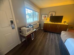 a room with a bedroom with a bed and a television at Naval Suites by FairBridge in Bremerton