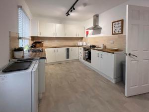 a large kitchen with white cabinets and a sink at 6 Mill Road in Okehampton