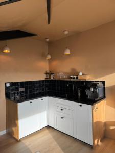 a kitchen with white cabinets and a black counter top at Maison Colombe, met airco in Oudesluis