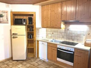 a kitchen with a white refrigerator and wooden cabinets at Haus Martin Appartement Eichhörnchen in Ramsau am Dachstein +5 photos
