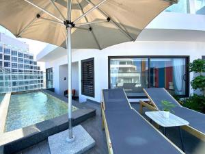 a patio with an umbrella and a swimming pool at Apec Mandala Wyndham ChamBay Mui Ne - LT in Mui Ne