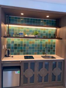 a kitchen with a sink and a green tiled wall at Apec Mandala Wyndham ChamBay Mui Ne - LT in Mui Ne