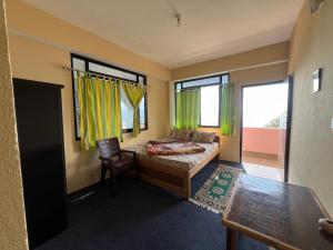 a bedroom with a bed and a desk and windows at Hangkhim Homestay in Ravangla