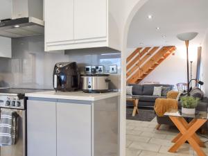 a kitchen with white cabinets and a living room at Mill House Barn in Warmingham