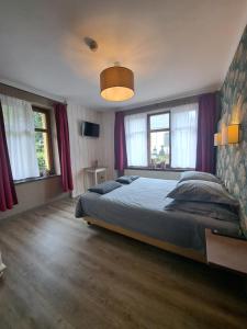 a bedroom with a large bed with purple curtains at Gîte des Roches in Cugnon