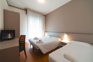 a hotel room with two beds and a television at Hotel Del Corso in Bibione