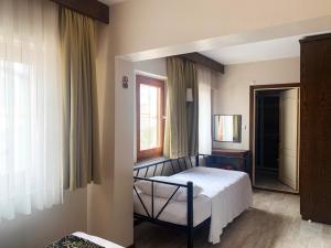 ein Schlafzimmer mit einem Bett, einem Fenster und einem Spiegel in der Unterkunft Mitos Hotel in Bozcaada