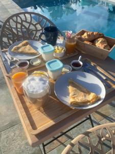 a table with breakfast food on it next to a pool at Vanille-colibris Le Domaine Mannou in Sainte-Rose