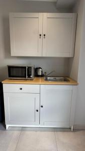 a white kitchen with a sink and a microwave at Apartamenty Odrodzenia 11 in Szczytno