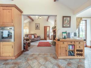 a living room with a kitchen with wooden cabinets at Beckside in Gilcrux
