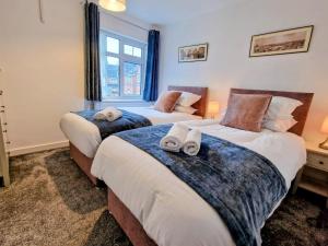 a bedroom with two beds with towels on them at Central modern home with parking in Nantwich