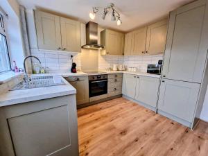 a kitchen with white cabinets and a wooden floor at Central modern home with parking in Nantwich +12 photos