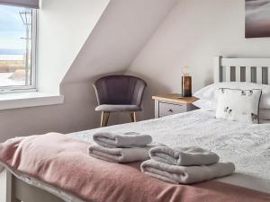 a bedroom with a bed with towels on it at The Shore in Fortrose